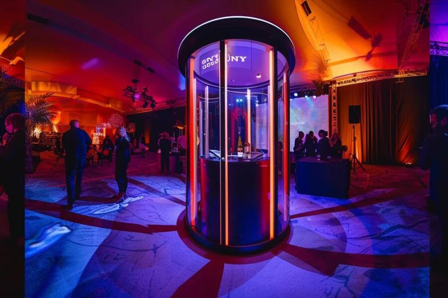 a sleek, modern 360 video booth, illuminated with vibrant led lights, stands at a lively event space in ryde, surrounded by excited guests capturing unforgettable moments in dynamic panoramic views.