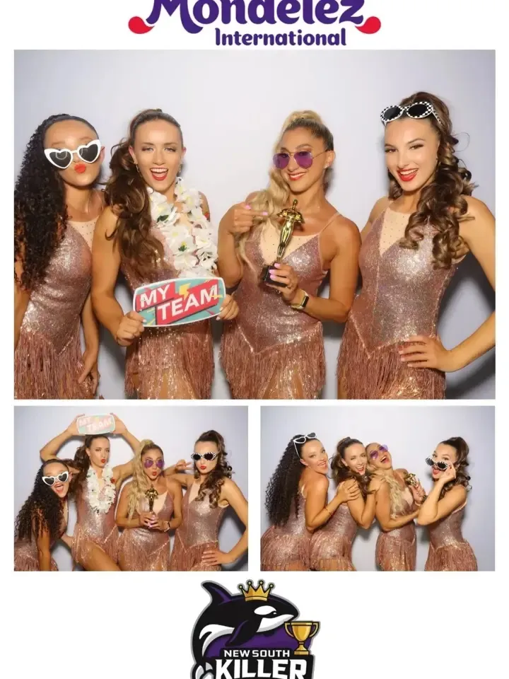 Four women in sparkling fringe dresses posing playfully with props, including a sign that reads "MY TEAM," in a photo booth setting, with a backdrop featuring the Mondelez International logo and the New South Wales Killer logo.