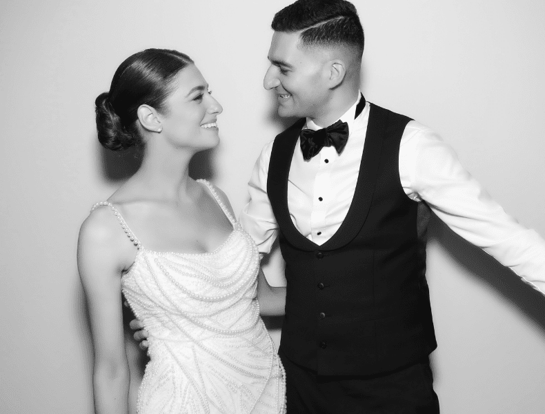 Bride and groom smiling at each other in elegant wedding attire, showcasing a joyful moment captured in a photo booth setting, reflecting HALO360's premium wedding photo booth experience.