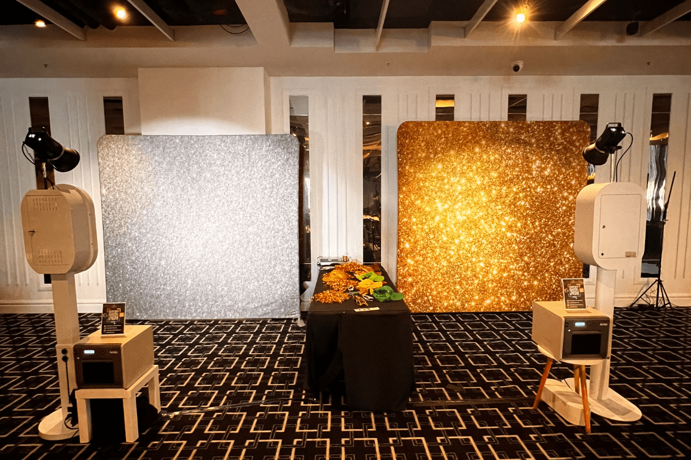 360 video booth setup with silver and gold glitter backdrops, props on a black table, and professional lighting for school formal events.