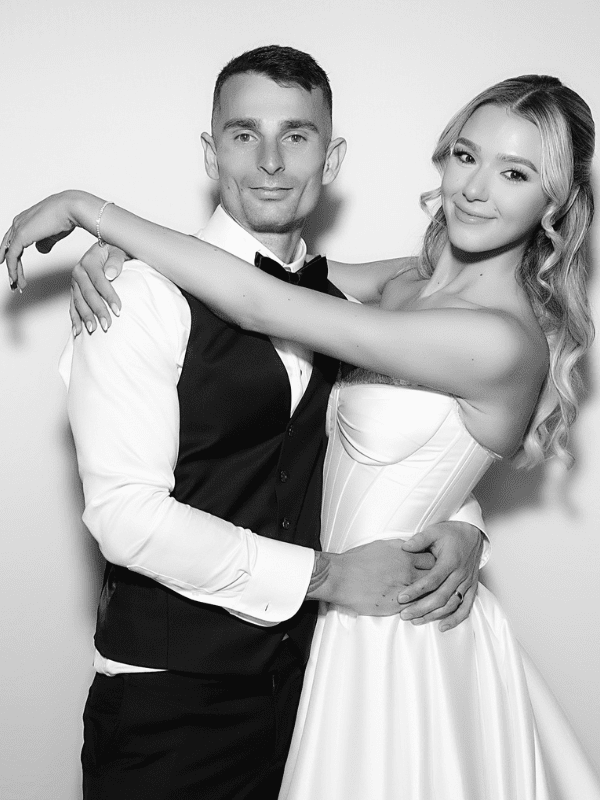 Couple embracing in a photo booth, dressed formally, capturing a joyful moment, ideal for wedding or corporate event celebrations.