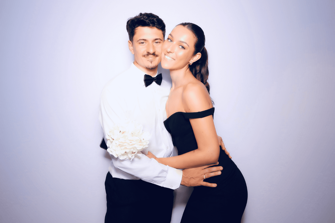 Couple posing together in elegant attire, showcasing a wedding-themed photo booth experience with a modern backdrop.