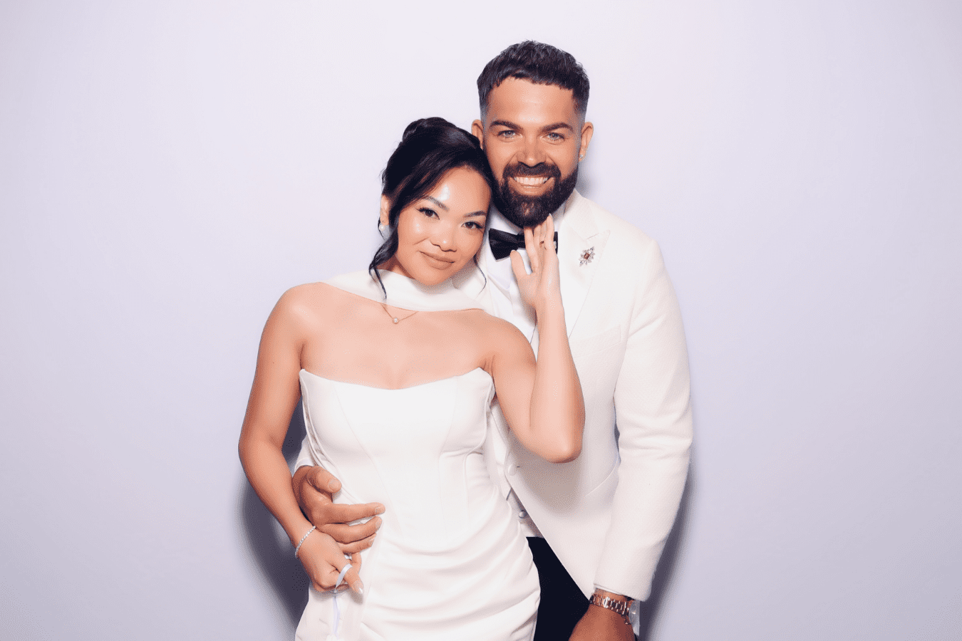 Couple in wedding attire, smiling and posing together, showcasing a joyful moment captured at a wedding photo booth experience.