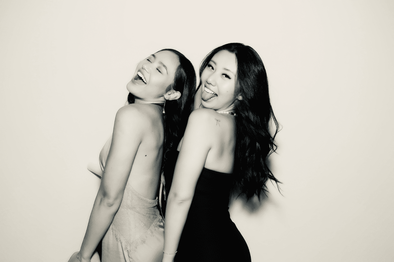 Two women posing playfully in stylish outfits, showcasing joyful expressions and fun interactions, representing a memorable moment at a wedding photo booth experience.