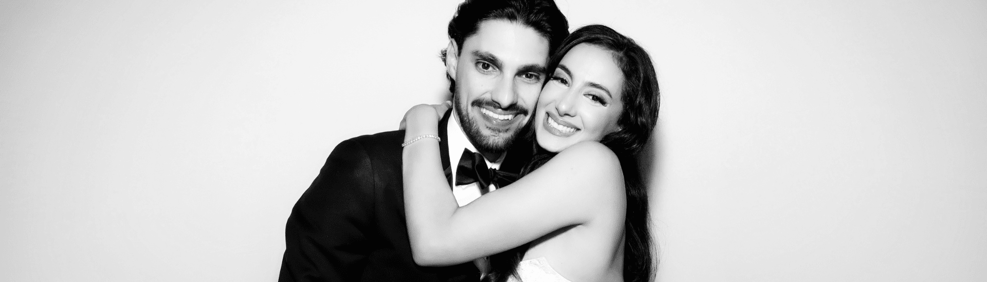 Couple embracing and smiling in a wedding photo booth, showcasing joyful moments and elegant attire, relevant to premium wedding photo booth services in Sydney.